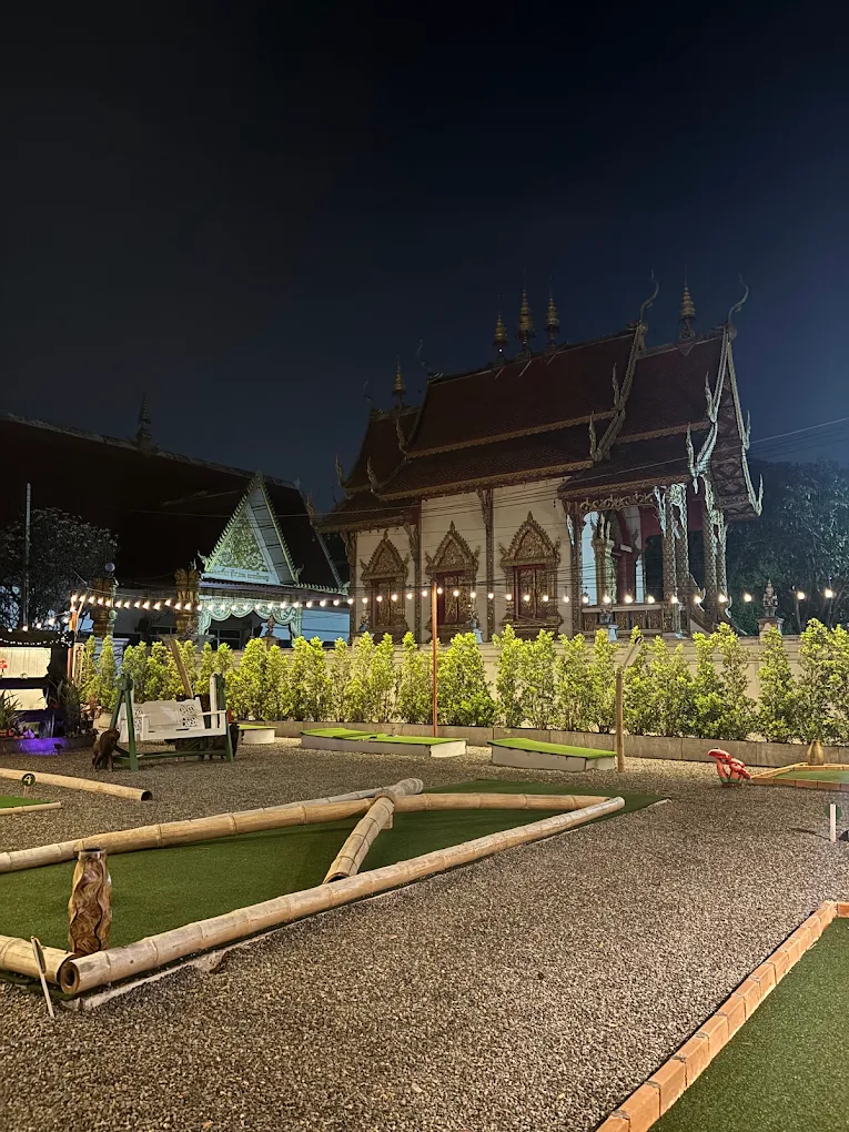 The mini golf course at night with an illuminated temple behind it